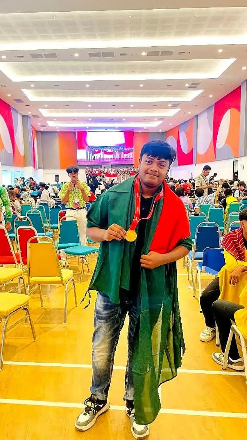 Md Saad Islam on stage receiving a gold medal, wearing a green and red shawl