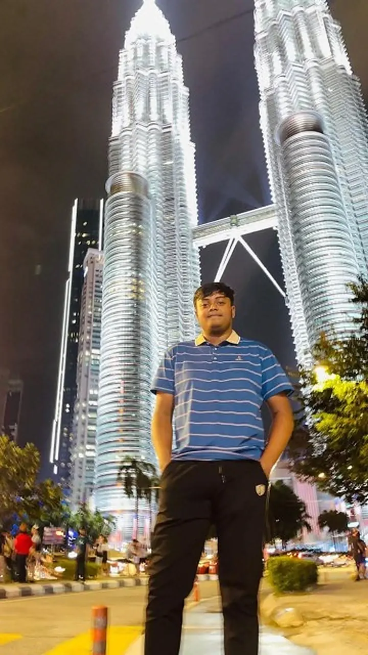 Md Saad Islam at night in front of the illuminated Petronas Towers