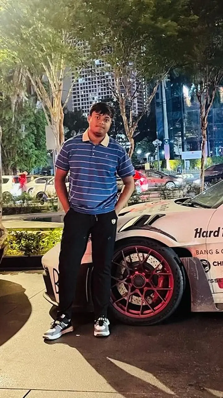 Md Saad Islam at night beside a white Porsche with red wheels